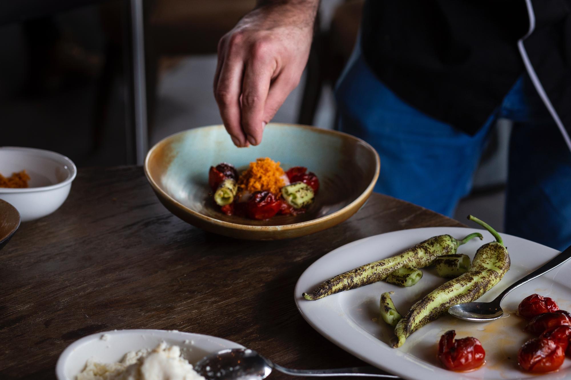 Chefs plating a modern dish on wooden table